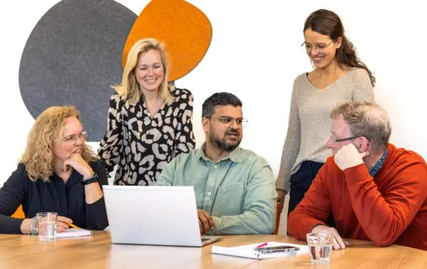 Collega's zitten met elkaar achter een laptop kennis te delen.