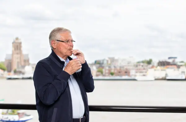 Man staat buiten en drinkt uit flesje drinkvoeding.