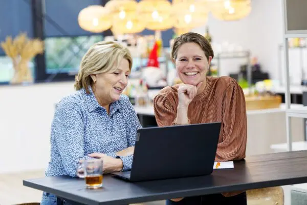 Monique Klepke en Ingrid Koppers samen achter de laptop.