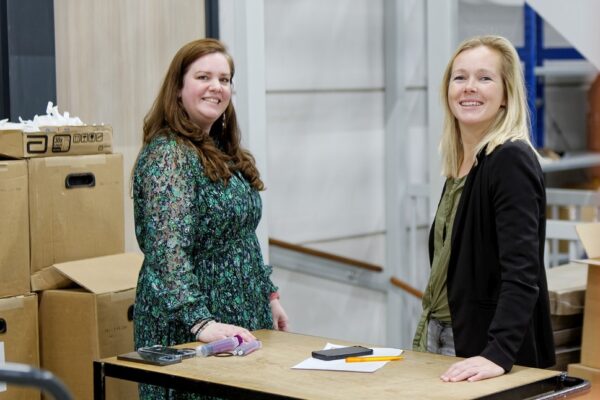 Twee collega's staan met elkaar te praten in het magazijn.